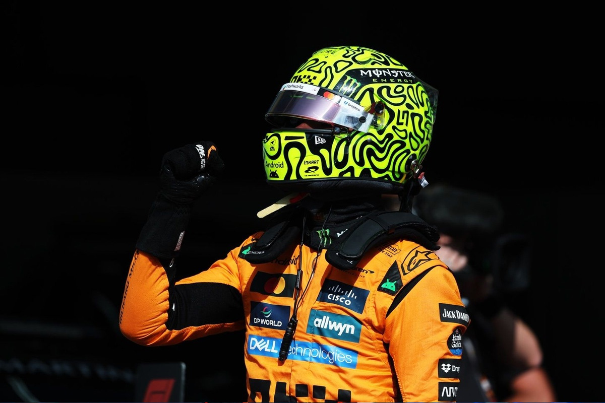 Lando Norris poing levé en tenue McLaren, casque jaune fluo après une victoire ou une qualification