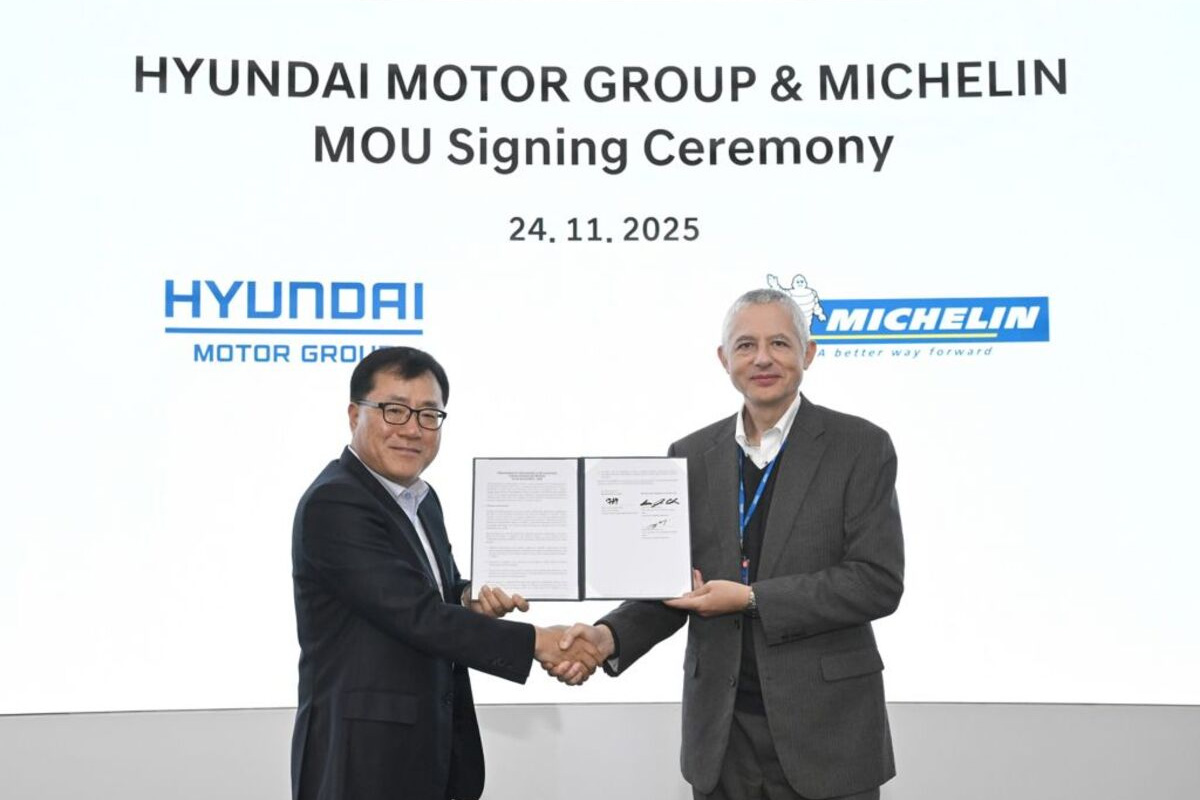 Représentants de Hyundai Motor Group et Michelin se serrant la main devant un panneau d’accord de partenariat